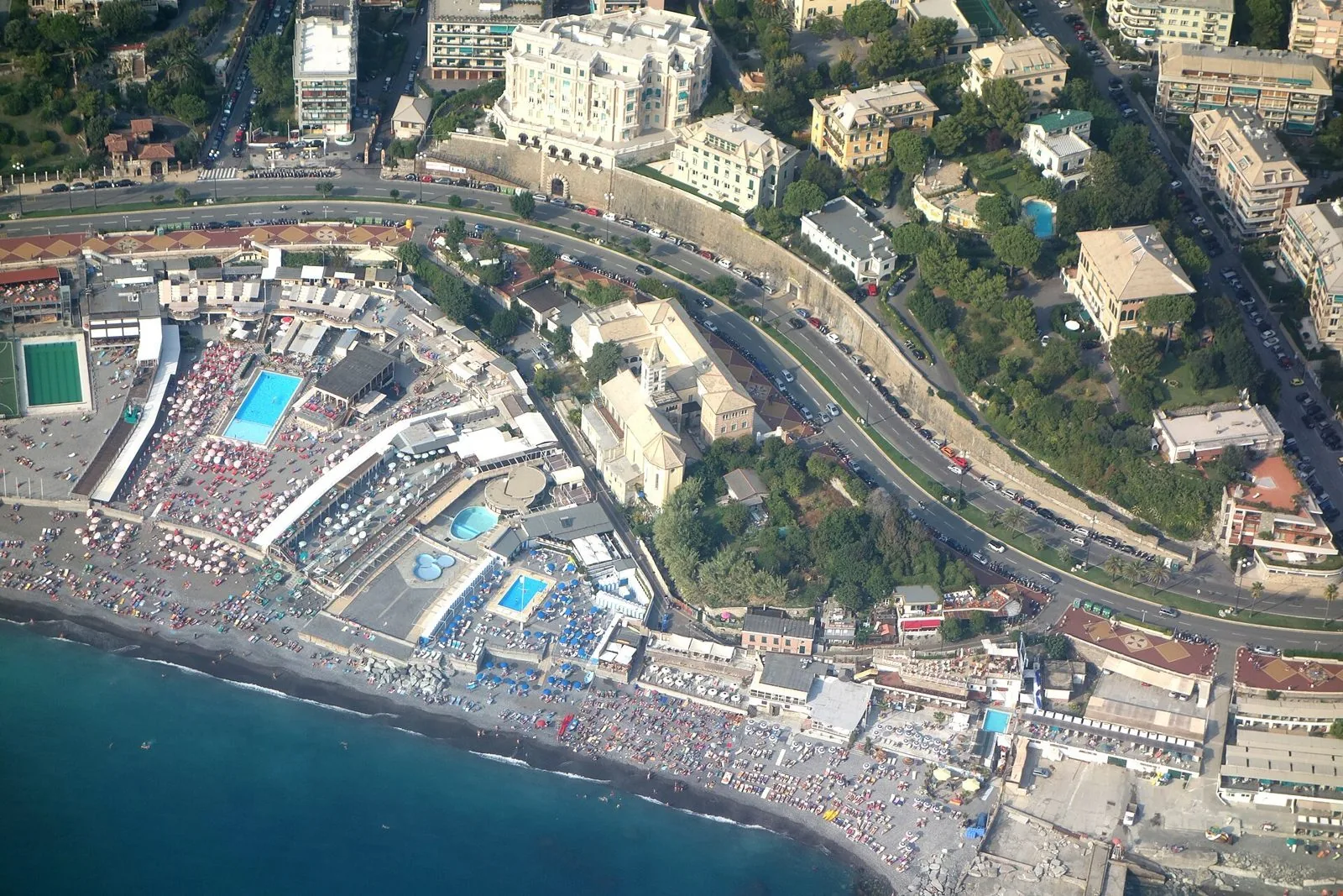 Veduta aerea estiva di Corso Italia a Genova con le spiagge affollate e il mare azzurro